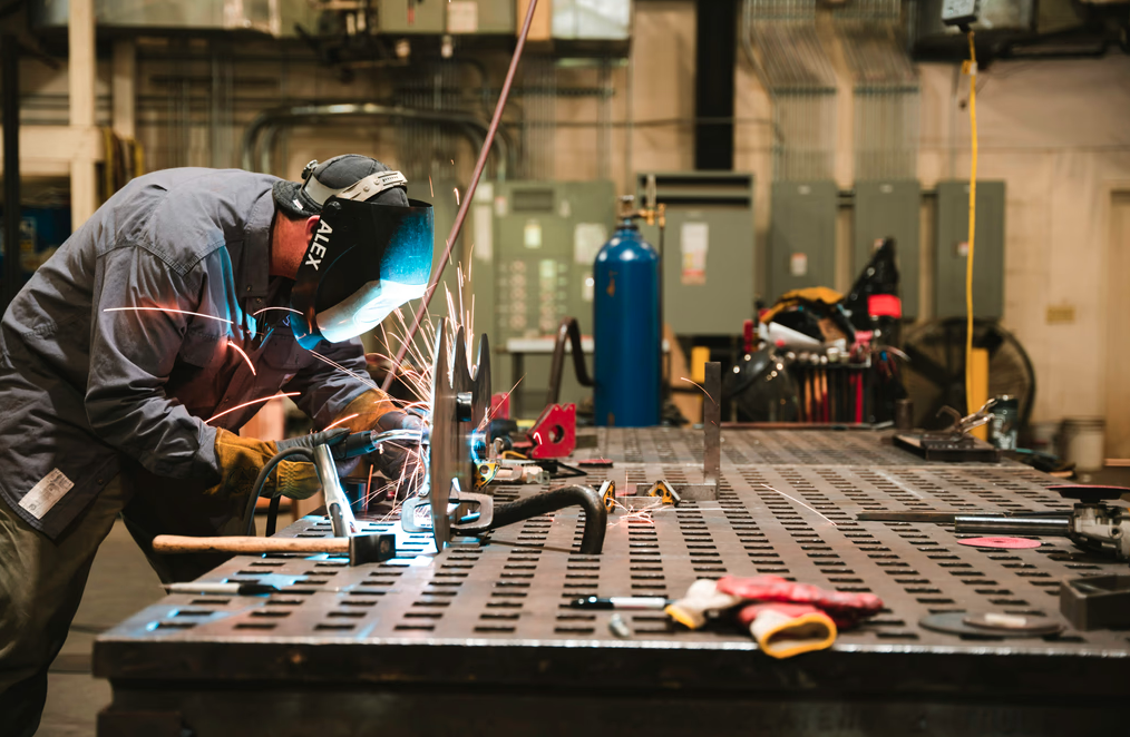 Employee owner welding in a manufacturing facility